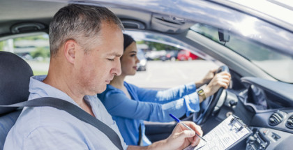Instructor of driving school giving exam while sitting in car. Student driver taking driving test. Driving instructor and woman student in examination car